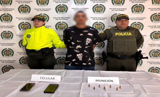 Dos policías de la SIJIN custodian a un capturado y elementos incautado