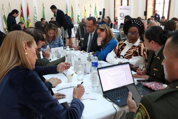 Personas reunidas en mesa de trabajo, diligenciando formato con cuestionario, como insumo para los estándares del comandante de estación