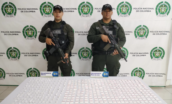 Hombre capturado en medio de dos polic&iacute;as, en frente estuperfacientes incautados