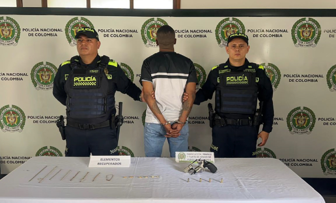 Hombre capturado en medio de dos policías, en frente elementos incautados