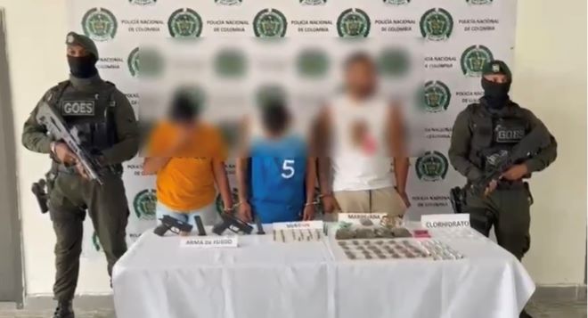 dos policías al lado de tres hombres capturados con material incautado