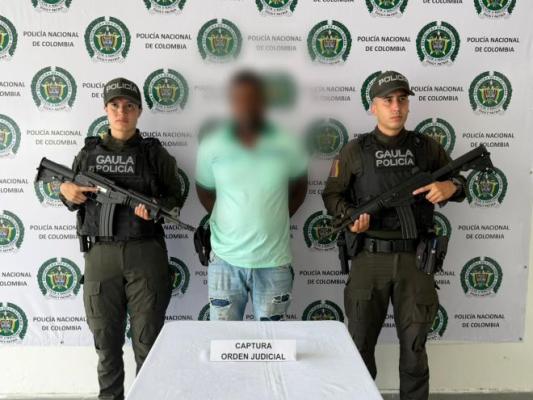 dos policías al lado de un hombre capturado por orden judicial