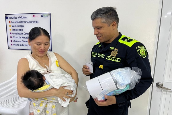 Señor Teniente Coronel Alex Muñoz entregando regalo a mamá con su hijo en brazos.